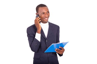 Ceketli yakışıklı iş adamı beyaz arka planda duruyor cep telefonuyla konuşuyor ve elinde gülümseyerek not defteri tutuyor..
