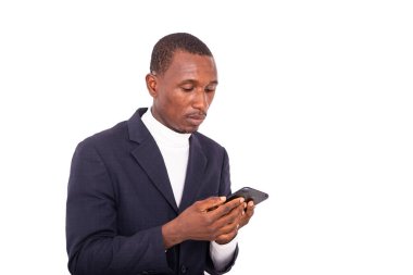 a handsome businessman in jacket standing on white background looking at cellphone.
