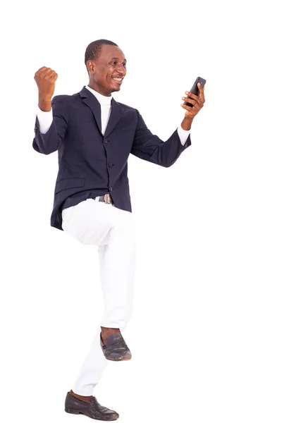 一个穿着夹克的英俊商人站在白色的背景上高兴地看着手机跳跃 — 图库照片