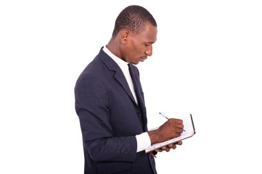 Ciddi, yetişkin bir işadamı elinde kalemle bir deftere yazı yazıyor..