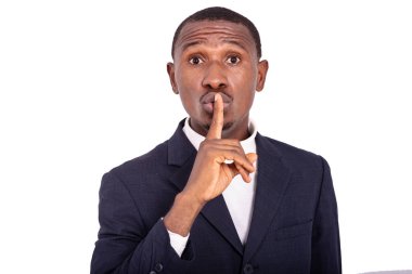 Yetişkin iş adamı kamerada sessiz bir jest yapıyor. Parmağı dudaklarında..