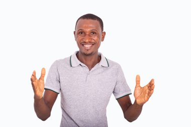 Beyaz arka planda duran gri tişörtlü genç adam gülümseyen bir şeyin büyüklüğünü gösteriyor..