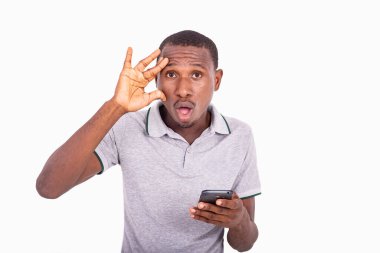 Elinde cep telefonu olan genç adam, şaşırmış görünüyordu, elleri yüzündeydi..