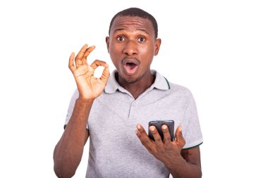 Elinde cep telefonu olan ve parmaklarıyla doğru hareketi yapan yakışıklı, şaşkın genç bir adam..