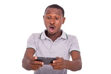 Yakışıklı genç adam içeride duruyor, şaşırmış görünüyor, ağzı açık, cep telefonuna bakıyor..