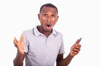 Cep telefonu tutan genç adam, ağzı açık, şok olmuş görünüyor..