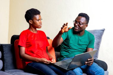 Evdeki kanepede dizüstü bilgisayar kullanarak oturan güzel bir çift..