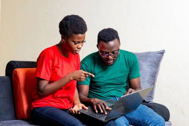 Evdeki kanepede dizüstü bilgisayar kullanarak oturan güzel bir çift..