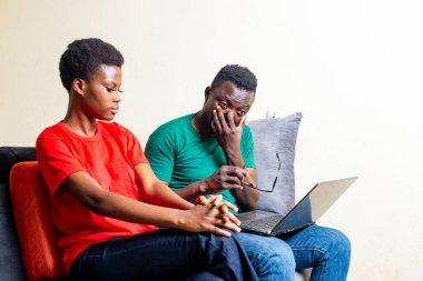 Evdeki kanepede dizüstü bilgisayarlarıyla oturan genç ve güzel bir çift..