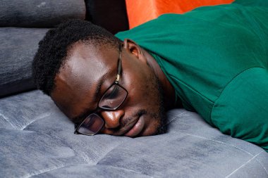 Gözlüklü genç işadamı oturma odasında kanepede uyumaktan yoruldu..