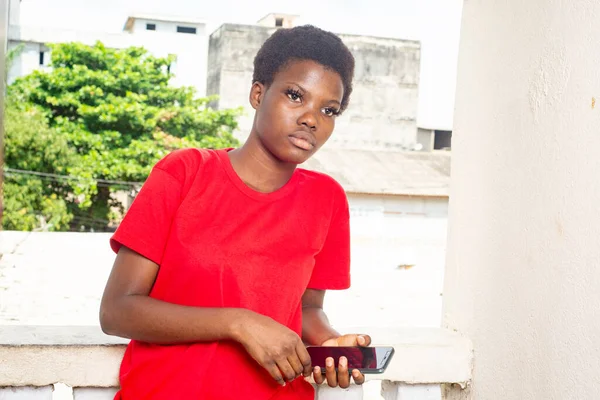Krásná Mladá Dívka Stojící Balkóně Domu Červeným Tričkem Mobilním Telefonem — Stock fotografie