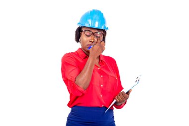 Güzel bayan mühendis mavi güvenlik kaskı takıyor, panoyu tutuyor ve parmaklarıyla gözlerini temizliyor..