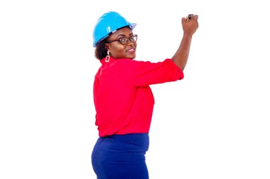 Güzel, yetişkin kadın mühendis mavi kasklı beyaz tahtaya yazarken gülümsüyor..