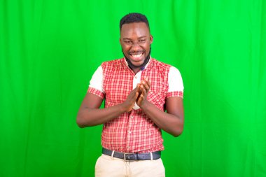 Gülümserken yeşil bir arkaplanda duran yakışıklı bir gencin portresi..