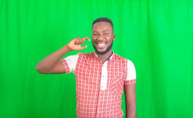 Yeşil arka planda duran yakışıklı bir gencin portresi ve gülümseyerek küçük bir jest yapıyor..