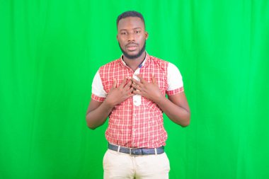 Kameraya bakarken iki elini de göğsüne koyan yakışıklı bir gencin portresi..