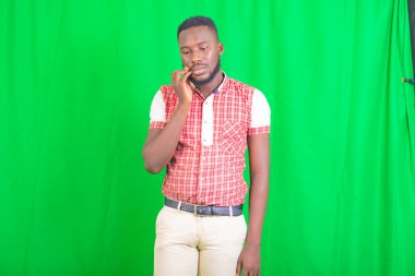 Yeşil arka planda duran yakışıklı bir gencin portresi hüzünlü ve sakin.