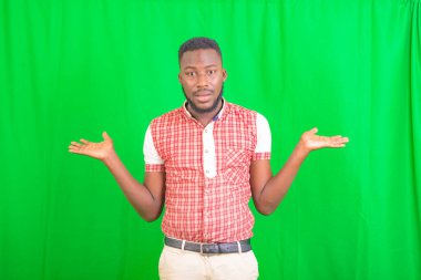 Yeşil arka planda duran ve avuçlarında boş alanlar tutan yakışıklı bir gencin portresi..