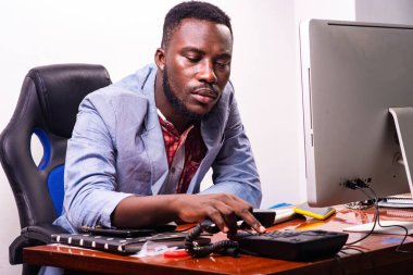 Yakışıklı genç iş adamı ofiste dizüstü bilgisayarın önünde oturuyor ve telefon ahizesinde numarayı çeviriyor..