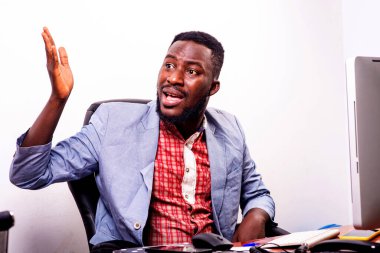 Yakışıklı, kızgın, genç iş adamı ofiste dizüstü bilgisayarla oturuyor ve elini hareket ettiriyor..