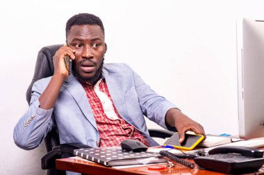 Ceketli iş adamı masada oturuyor ve cep telefonuyla konuşuyor..