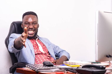 Ceketli bir işadamı masasında oturmuş gülüşünü gösteriyor..