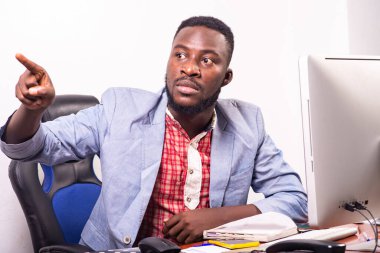 Genç iş adamı dizüstü bilgisayarın karşısında oturuyor ve parmağını bir tarafa gösteriyor..