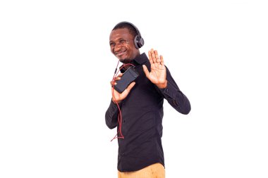 Tişörtlü bir öğrenci beyaz arka planda duruyor. Cep telefonu ve kulaklık kullanarak müzik dinliyor. Reddetme hareketi yapıyor.