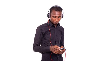 Beyaz arka planda duran bir öğrenci cep telefonu ve kulaklık kullanarak müzik dinliyor..