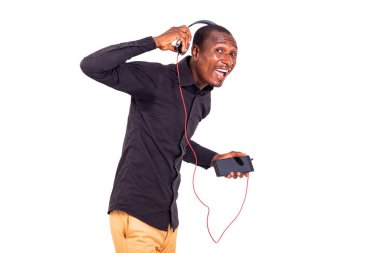 Tişörtlü bir öğrenci beyaz arka planda durup biriyle konuşurken telefon ve kulaklık kullanarak müzik dinliyor.