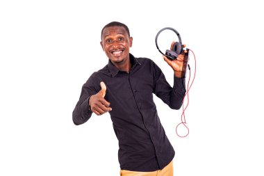 Beyaz arka planda oturan bir öğrenci elinde kulaklık ve cep telefonu tutarken gülüyor..