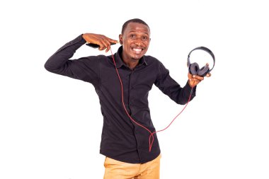 Beyaz arka planda duran, kulaklığı işaret eden, gülümseyen bir öğrenci.