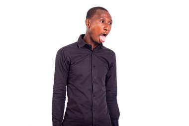 Beyaz arka planda duran tişörtlü bir öğrenci komik bir ifadeyle dilini dışarı çıkarıyor..