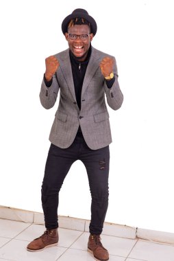 Yakışıklı genç bir işadamının portresi şık bir takım elbise giyiyor ve kollarını kaldırıp gülümserken zafer jesti yapıyor..