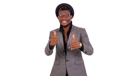 Yakışıklı genç bir işadamının portresi şık bir takım elbise giyiyor ve gülümserken başparmaklarını kaldırıyor..