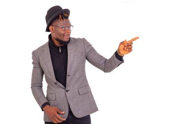 Yakışıklı genç bir işadamının portresi şık bir takım elbise giyiyor ve gülümserken parmağıyla işaret ediyor..