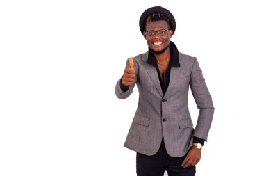 Yakışıklı, iyi giyimli genç bir iş adamının gülümseyerek baş parmağını gösteren portresi..