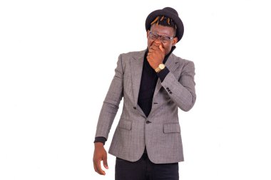 Yakışıklı, yorgun, genç bir iş adamının portresi. Zarif bir takım elbise giyiyor ve eli ağzında esniyor..