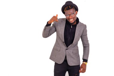 Zarif bir takım elbise giymiş yakışıklı bir iş adamının portresi ve parmaklarıyla cep telefonu hareketi yaparken gülümsüyor..