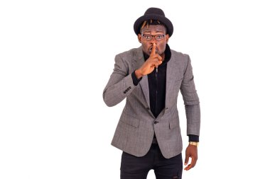 Zarif bir takım elbise giyen yakışıklı bir iş adamının portresi ve dudaklarında parmaklarıyla sessizlik işareti..