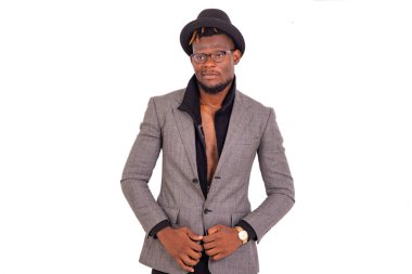 Yakışıklı, genç bir iş adamı. Kafasında siyah bir şapka olan şık bir takım elbise giyiyor..