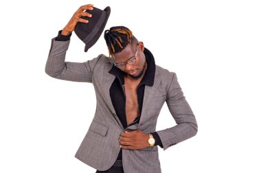 Yakışıklı, genç bir iş adamı. Kafasında siyah bir şapka olan şık bir takım elbise giyiyor..