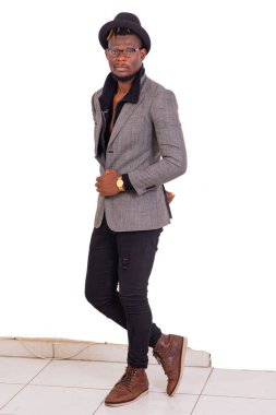 Yakışıklı, genç bir iş adamı. Kafasında siyah bir şapka olan şık bir takım elbise giyiyor..