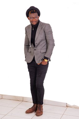 Yakışıklı genç bir işadamı şık bir takım elbise giyiyor ve iki elini de pantolonunun cebinde tutuyor..