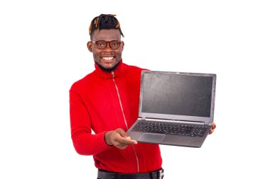 Yakışıklı genç adam kırmızı kazak giyiyor ve elinde dizüstü bilgisayarla gülümsüyor..