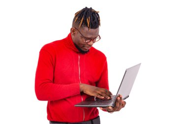 Kırmızı kazak giyen yakışıklı genç adam dizüstü bilgisayar kullanıyor..