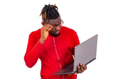 Optik gözlük takan yakışıklı genç bir adam dizüstü bilgisayarın ekranında bir şeye bakıyor..