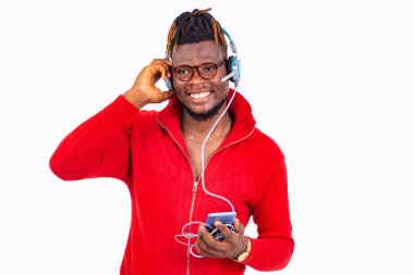 Gözlüklü genç bir adam beyaz arka planda duruyor cep telefonuyla iletişim kuruyor, gülüyor..