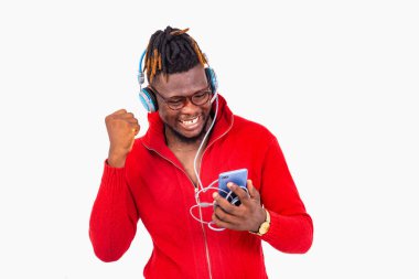 Gözlüklü genç bir adam beyaz arka planda duruyor cep telefonuyla iletişim kuruyor ve zafer işareti gösteriyor..