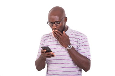 Elle ağızla optik gözlük takan genç adam cep telefonundan kötü haberlere bakıyor..